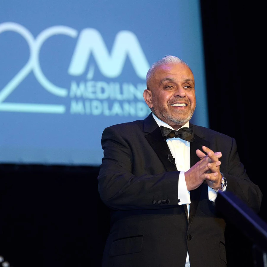 Host in formal attire on stage at a corporate awards ceremony