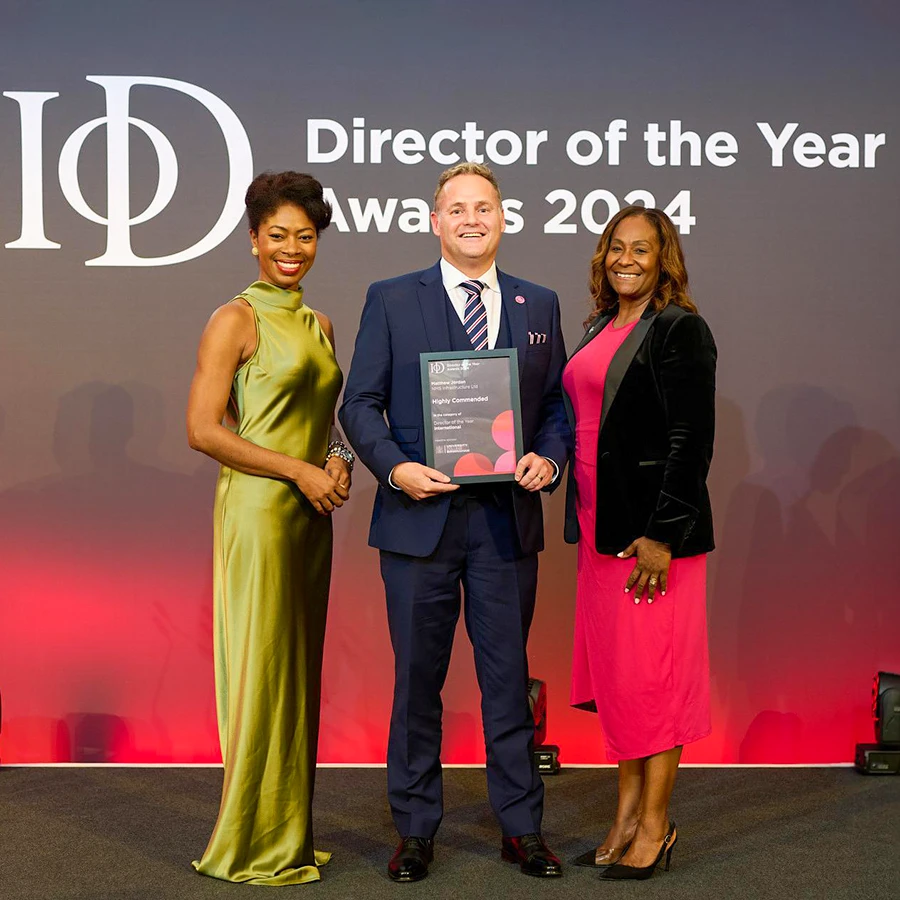 Award recipient with presenters on stage at the Directors Awards 2024