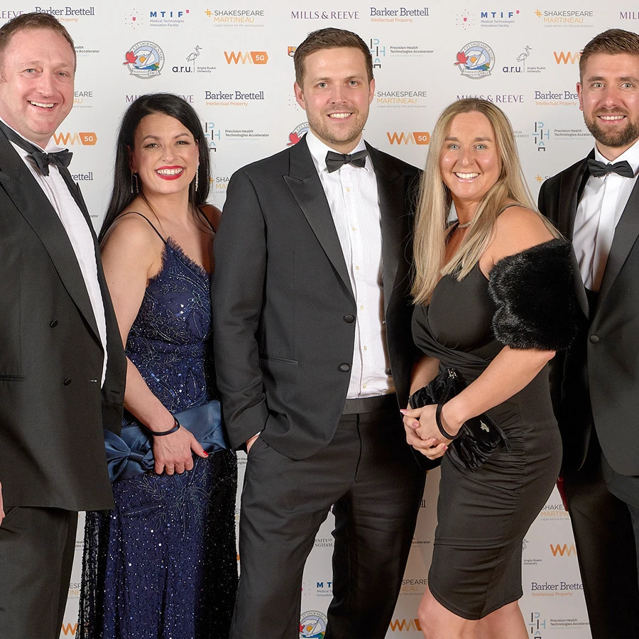 Group of guests posing in front of sponsor backdrop at corporate awards